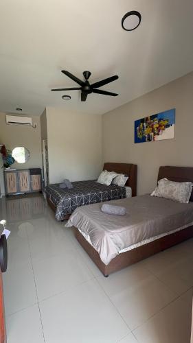 a bedroom with two beds and a ceiling fan at Homestay Babah - Private Chalet in Malacca