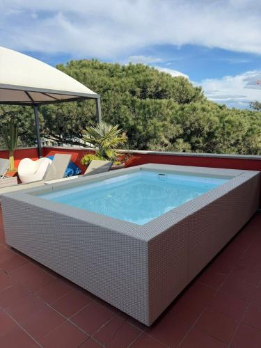 a pool on a roof with chairs and an umbrella at Hotel 1908 in Forte dei Marmi