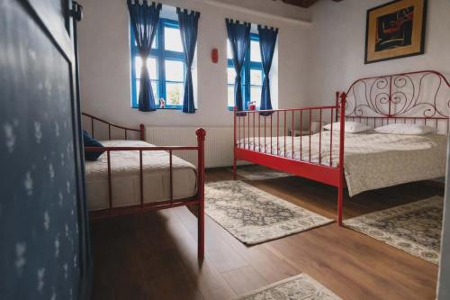 a bedroom with two beds and two windows at Kékfestő Vendégház in Bükkszentkereszt