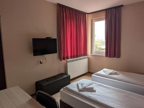 a hotel room with two beds and a flat screen tv at Hotel Poli in Blagoevgrad