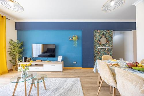 a living room with a blue wall and a table at T4 Espaçoso Perto da Praia e Aeroporto in Machico