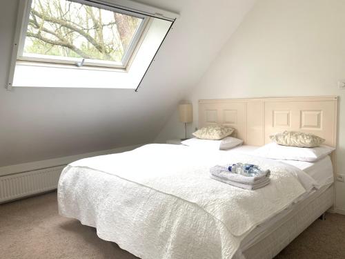 a bedroom with a large white bed with a window at Gezellig Cottage Markdal met gratis fietsen in Breda