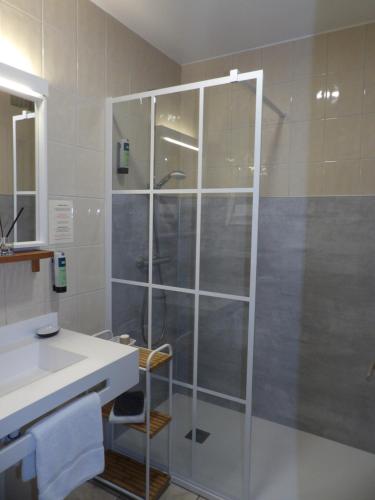 a bathroom with a glass shower with a sink at Logis Hotel Restaurant Le Jardin Délice in Saint-Victor