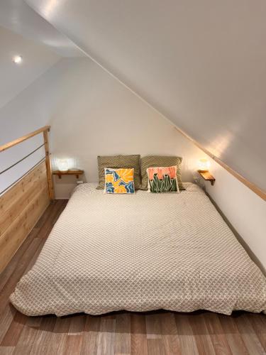 a bedroom with a bed with pillows on it at Aux Pas Sages, 4 logements mitoyens, proche mer in Saint-Jean-de-Monts