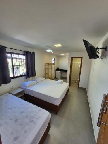 a hotel room with two beds and a television at Apart Suítes Praia Do Morro 5 a 7 dias e Barato in Guarapari