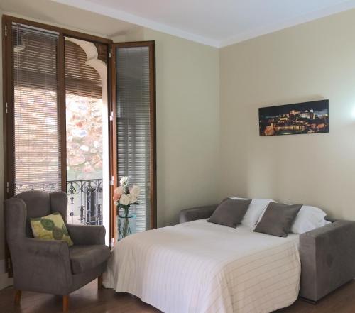 1 dormitorio con 1 cama, 1 silla y 1 ventana en Caesarina, en Cáceres