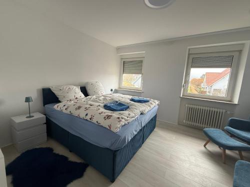 ein Schlafzimmer mit einem Bett, einem Stuhl und zwei Fenstern in der Unterkunft Traumwelt in Flemlingen