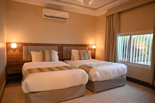 a hotel room with two beds and a window at شاطئ العرب الرايس in Rayyis