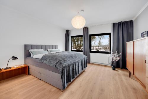 a bedroom with a large bed and two windows at Stilvoller Bauhaus Bungalow mit Sauna in Lüneburger Heide für 8 Gäste in Wohlendorf