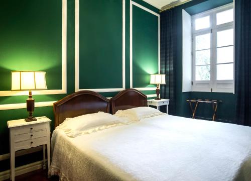 a green bedroom with a bed and a window at Casa Vitoriana in Ponta Delgada