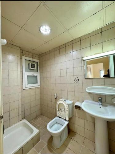 a bathroom with a toilet and a sink and a tub at Intermass building in Sharjah