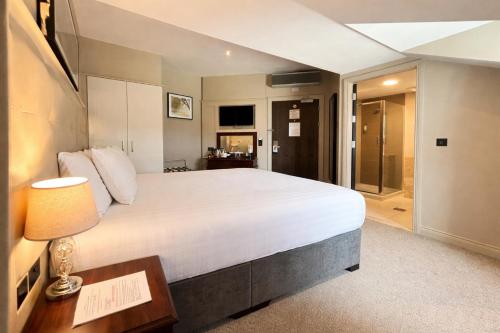 a bedroom with a large white bed and a bathroom at Hotel Rue in Omagh