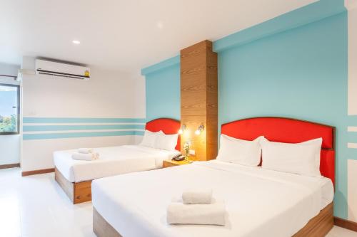 a bedroom with two beds and a red headboard at We Briza Hotel Chiangmai in Chiang Mai