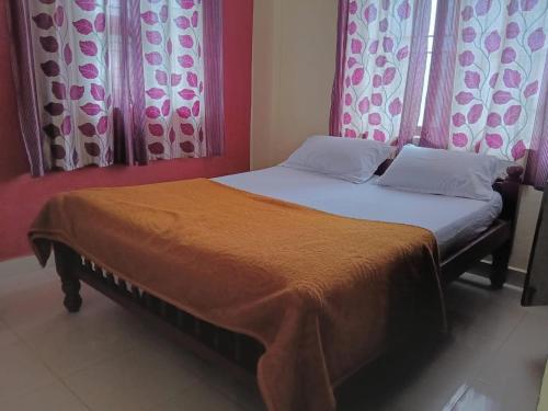 a bed with two pillows and a blanket on it at Coorg villa homestay in Madikeri