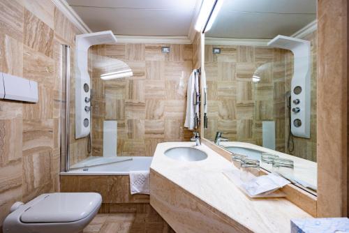a bathroom with a sink and a tub and a toilet at Etrusco Arezzo Hotel - Sure Hotel Collection by Best Western in Arezzo