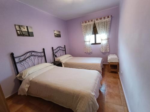 two beds in a room with purple walls at Casa Rural Javier in Valmuel
