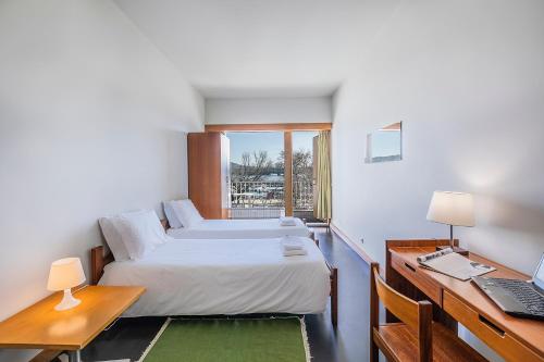 a bedroom with a bed and a desk with a laptop at HI Viana do Castelo - Pousada de Juventude in Viana do Castelo