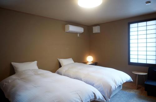 two white beds in a room with a window at 一棟宿 倉持 in Kusatsu