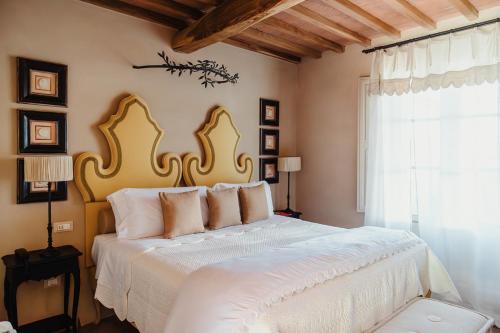 a bedroom with a large white bed with a large window at Relais Sant'Elena in Bibbona