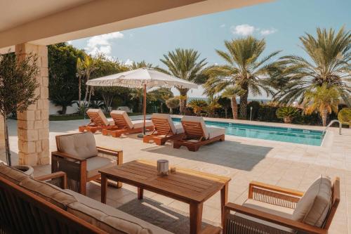 a patio with chairs and a table and a pool at Stylish villa with sea view in Peyia