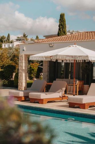 a swimming pool with lounge chairs and an umbrella at Stylish villa with sea view in Peyia