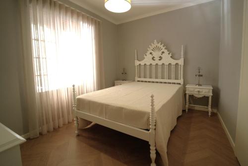 a bedroom with a white bed and a window at Casa Ti Madalena in Arganil
