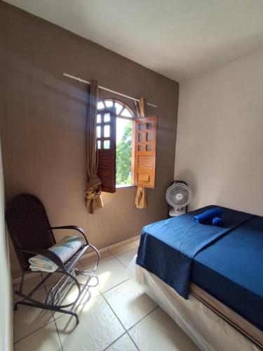 a bedroom with a bed and a chair and a window at Silsol in Itacaré
