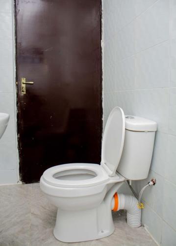 a bathroom with a toilet with a brown door at Shanny's Cozy Studio in Eldoret