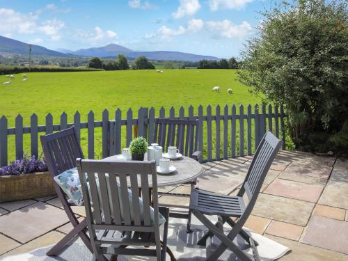 a table and chairs on a patio with a fence at Pencefn Cottage in Llanddeiniolen
