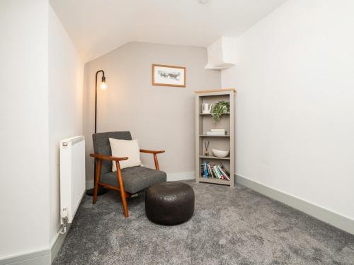 a living room with a chair and a ottoman at Pencefn Cottage in Llanddeiniolen