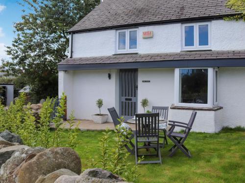 a house with two chairs and a table in the yard at Pencefn Cottage in Llanddeiniolen