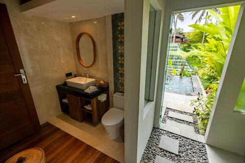 a bathroom with a toilet and a sink and a mirror at The Dura Ubud in Ubud