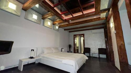 a bedroom with a white bed and some windows at Vendi Grand Square Residence in Sibiu