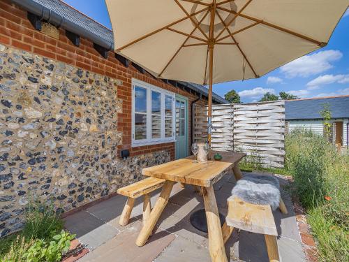 a wooden picnic table with an umbrella on a patio at Swallow - Uk50155 in Faversham