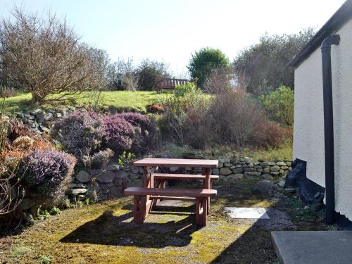 a wooden picnic table sitting next to a stone wall at Belloch Cottage in Glenbarr