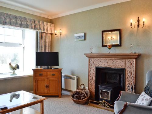 a living room with a fireplace and a tv at Belloch Cottage in Glenbarr