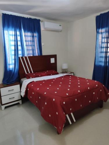a bedroom with a red and white bed with blue curtains at Casa Nury in Santo Domingo