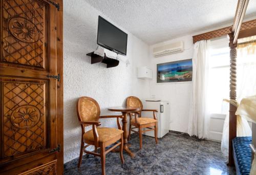 a room with two chairs and a table and a tv at Hotel Porto Perissa in Perissa