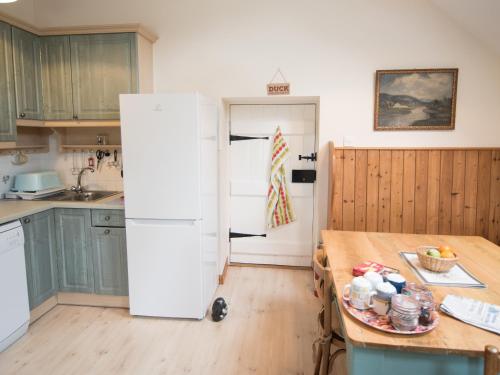 a kitchen with a white refrigerator and a table at Coachman's Bothy - Ukc5958 in Port Appin