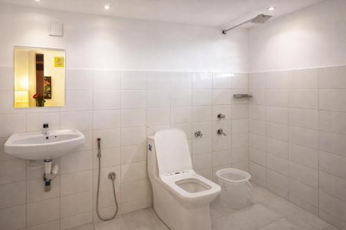 a white bathroom with a toilet and a sink at Skylora Heights Inn in Kozhikode