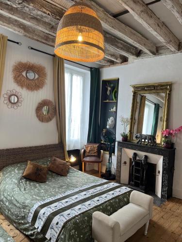 a bedroom with a bed and a chair and a mirror at Les Petites Mirabelles - À 9mn du ZooParc de Beauval - Gare à 200m - Route des Châteaux de la Loire in Noyers-sur-Cher