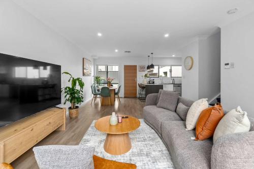 a living room with a couch and a table at Steps to the Beach Cafes moderm stylish 3BR in Christies Beach