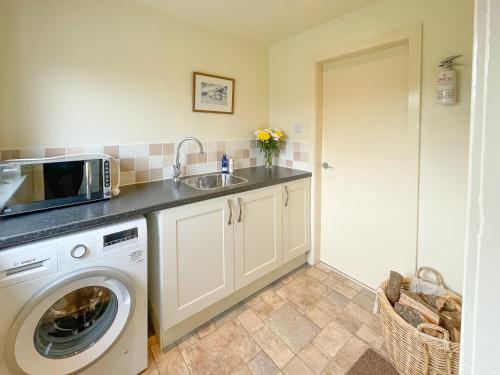a kitchen with a washing machine and a sink at Aird House in Ardfern