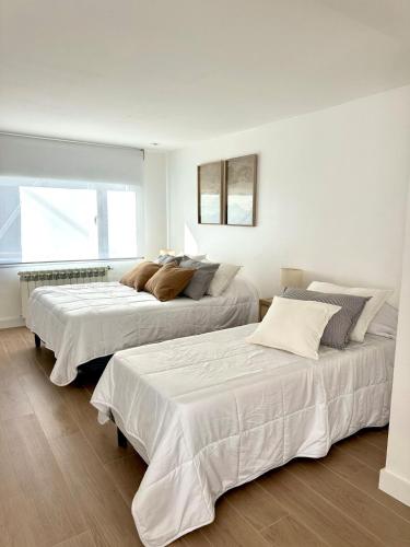 two beds in a room with white walls at Apart Exclusivo a Estrenar - Tu Base Perfecta in El Calafate