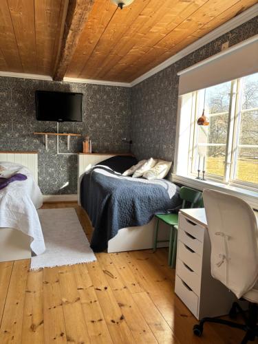 a bedroom with a bed and a desk and a tv at Torpidyll nära sjö in Vetlanda