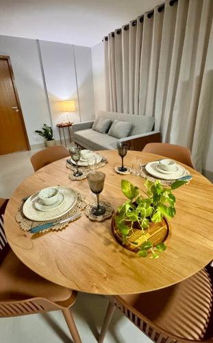 a wooden table with plates and wine glasses on it at Flat Aconchego no Setor Oeste a 50m do Lago das Rosas, apto novo in Goiânia