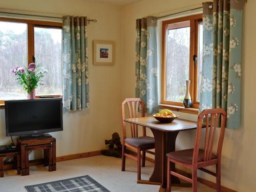 a living room with a television and a table with chairs at Birch Lodge - 28880 in Torcastle
