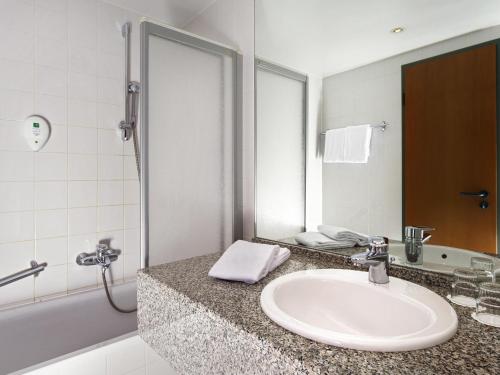 a bathroom with a sink and a mirror at Congress Hotel Weimar by Mercure in Weimar