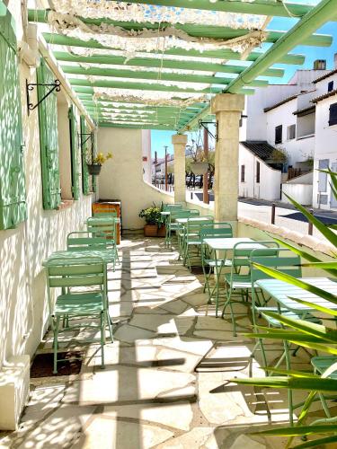 a row of green chairs and tables on a patio at Hotel Lou Marquès in Saintes-Maries-de-la-Mer