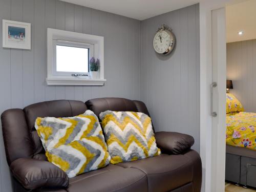 a brown couch with yellow and white pillows in a room at The Shepherd's Hut in Montrose